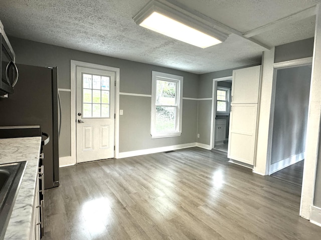 kitchen with a textured ceiling, light hardwood / wood-style flooring, a wealth of natural light, and white cabinetry