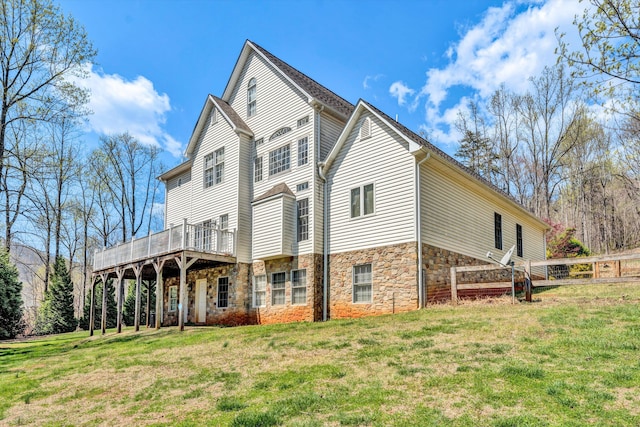 view of home's exterior featuring stone siding, a lawn, and a wooden deck