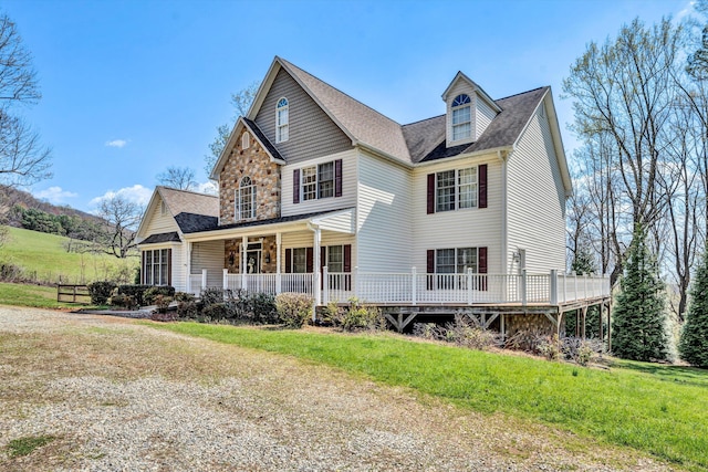 view of front of house featuring stone siding, roof with shingles, and a front yard