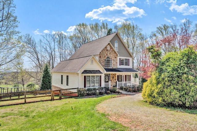 view of front facade with stone siding, fence, a porch, and a front yard