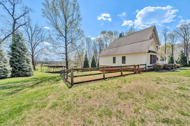 view of side of property with a shingled roof, fence, and a lawn