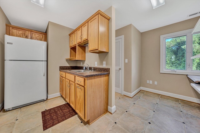 kitchen featuring light tile floors, white refrigerator, and sink