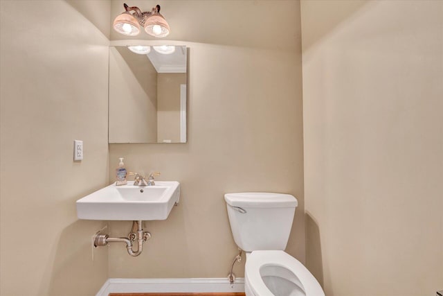bathroom with sink, toilet, and ornamental molding