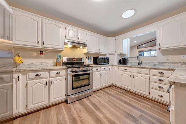 kitchen with white cabinets, light hardwood / wood-style floors, light stone countertops, and appliances with stainless steel finishes