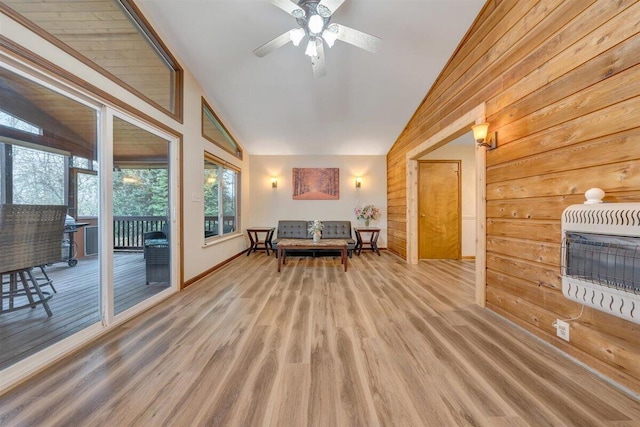 interior space featuring ceiling fan, heating unit, wood walls, wood-type flooring, and lofted ceiling