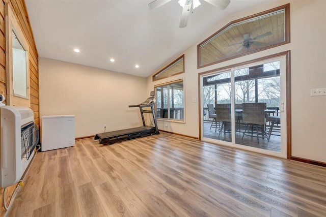 workout area featuring heating unit, vaulted ceiling, ceiling fan, and light hardwood / wood-style flooring