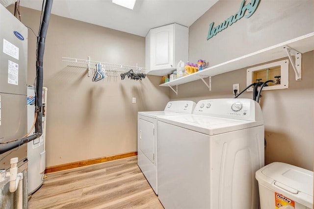 laundry room with cabinets, light hardwood / wood-style floors, washing machine and dryer, and heating unit