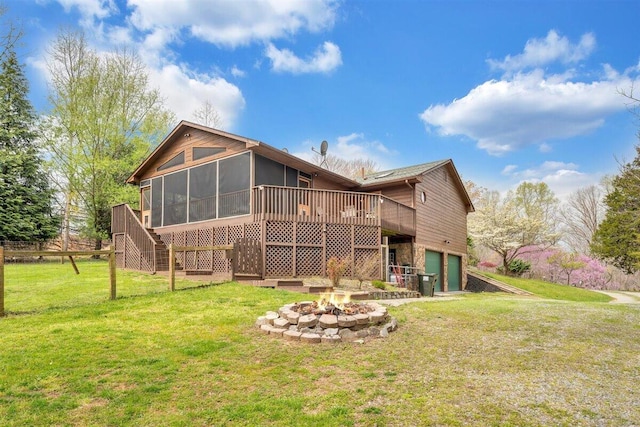 back of property with a sunroom, a yard, an outdoor fire pit, a deck, and a garage