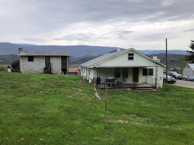 rear view of property featuring a lawn, covered porch, and a mountain view