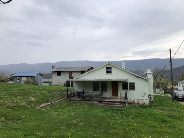 rear view of house with a mountain view, covered porch, and a yard