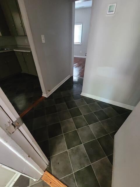 interior space with dark tile patterned floors and baseboards