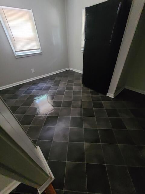 unfurnished room featuring dark tile patterned floors and baseboards