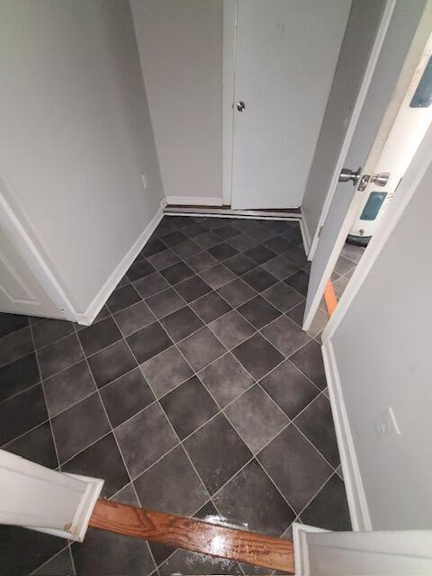 foyer featuring dark tile patterned flooring and baseboards