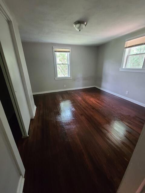 unfurnished room with dark wood-style floors and baseboards