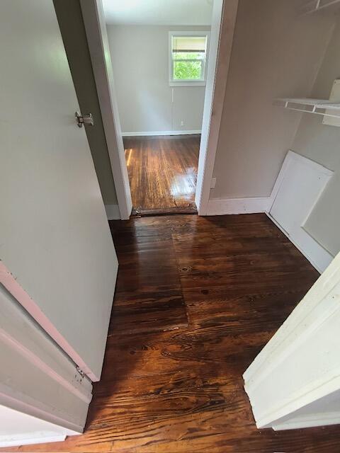 corridor with baseboards and wood finished floors