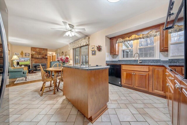 kitchen with ceiling fan, sink, a kitchen island, dishwasher, and a fireplace