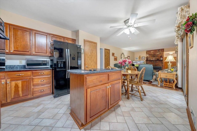 kitchen with dark stone counters, stainless steel appliances, ceiling fan, and a center island