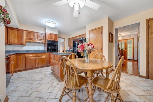 kitchen featuring ceiling fan, light hardwood / wood-style floors, tasteful backsplash, and black appliances