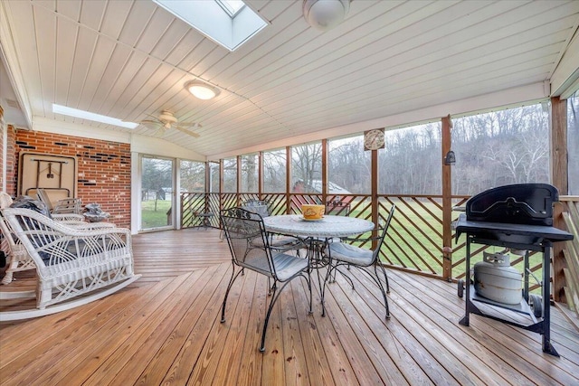 sunroom featuring ceiling fan, wood ceiling, lofted ceiling with skylight, and a healthy amount of sunlight