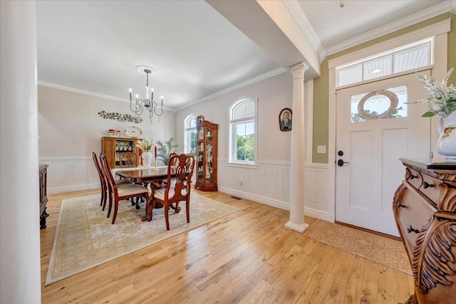 entrance foyer featuring a chandelier, ornamental molding, light hardwood / wood-style floors, and ornate columns