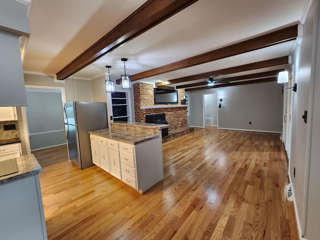 kitchen with beamed ceiling, light hardwood / wood-style flooring, stainless steel refrigerator, and dark stone countertops