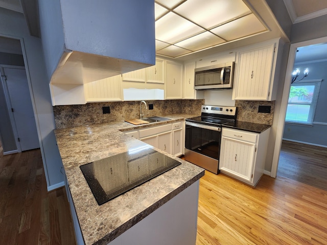 kitchen with white cabinetry, sink, stainless steel appliances, and a notable chandelier