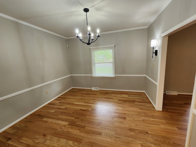 empty room with hardwood / wood-style floors, an inviting chandelier, and ornamental molding