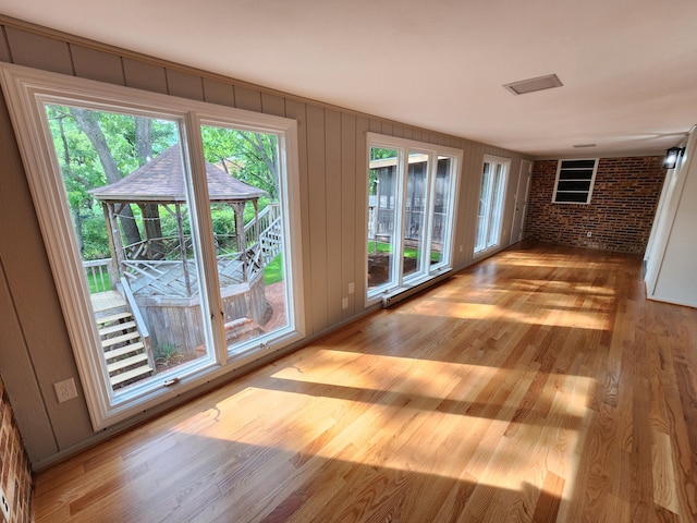 interior space with brick wall and hardwood / wood-style flooring