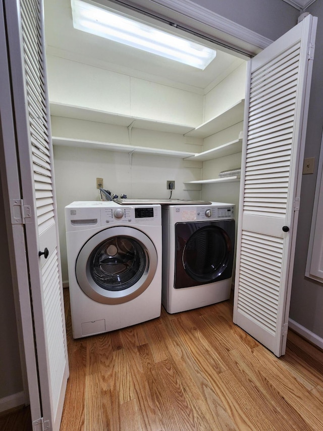 laundry area with washer and dryer and light hardwood / wood-style floors