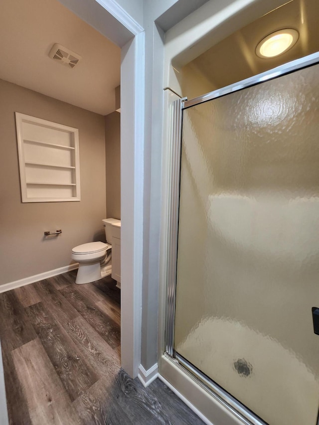 bathroom featuring built in shelves, hardwood / wood-style floors, toilet, a shower with door, and vanity