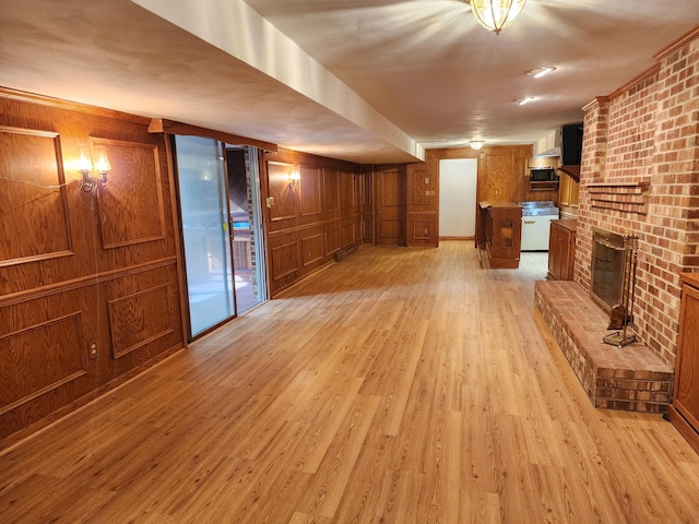 unfurnished living room featuring wood walls, a fireplace, and light hardwood / wood-style flooring