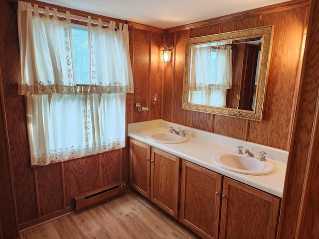 bathroom with vanity, hardwood / wood-style flooring, baseboard heating, and wood walls