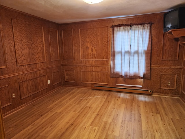 unfurnished room with wooden walls, a baseboard radiator, and light wood-type flooring