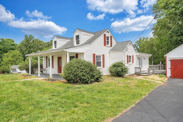 cape cod house featuring a front yard, a garage, an outdoor structure, and a porch