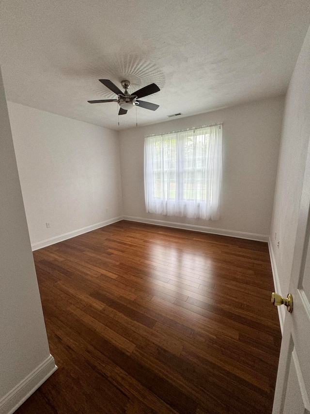 spare room with a textured ceiling, ceiling fan, and dark hardwood / wood-style floors