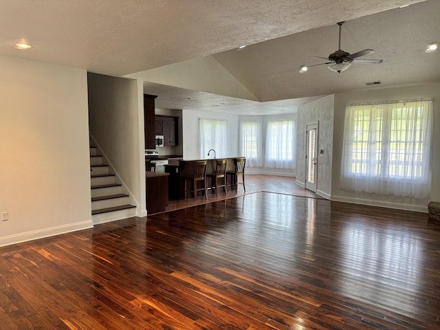 unfurnished living room with ceiling fan, vaulted ceiling, and dark hardwood / wood-style flooring