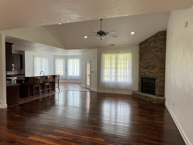 unfurnished living room featuring plenty of natural light, vaulted ceiling, a fireplace, and hardwood / wood-style flooring