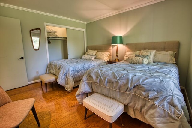 bedroom with wood-type flooring, a closet, and crown molding