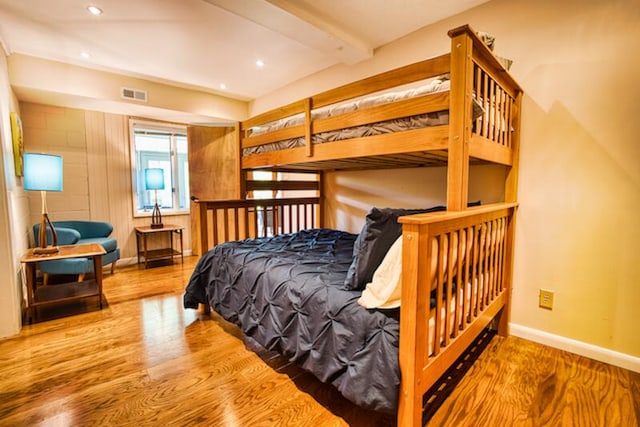 bedroom with beam ceiling and wood-type flooring