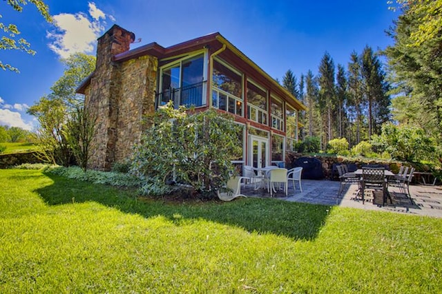 rear view of house featuring a lawn and a patio