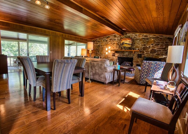 dining area with wood-type flooring, lofted ceiling with beams, wood ceiling, and a fireplace