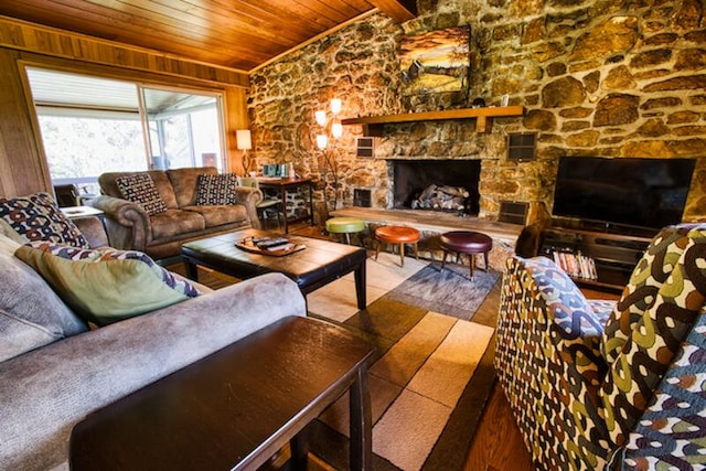 living room featuring a stone fireplace, vaulted ceiling, wood ceiling, and wood-type flooring