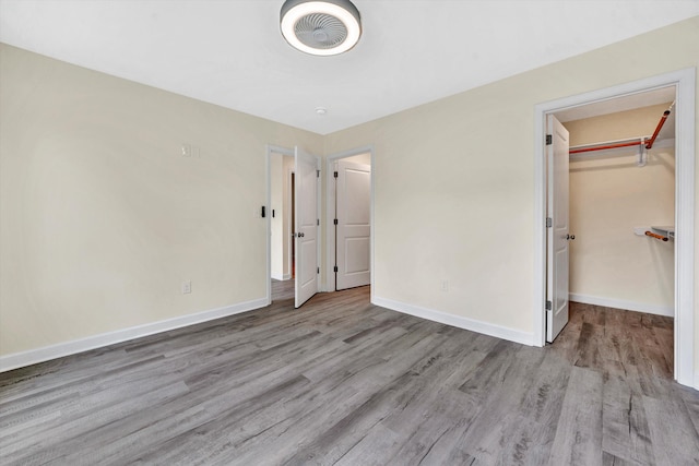 unfurnished bedroom featuring a closet, a spacious closet, and light hardwood / wood-style flooring