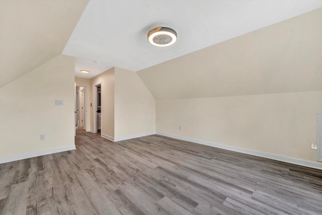 additional living space with light hardwood / wood-style floors and vaulted ceiling