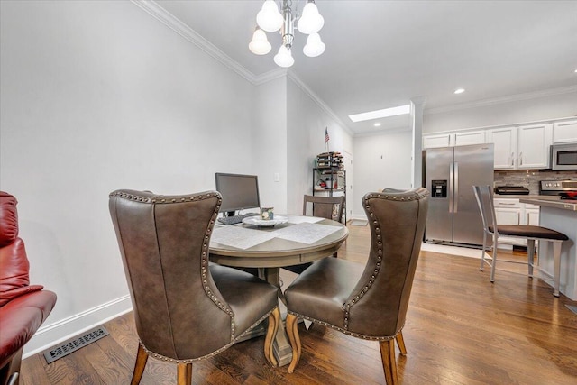 dining space with a notable chandelier, ornamental molding, and light wood-type flooring