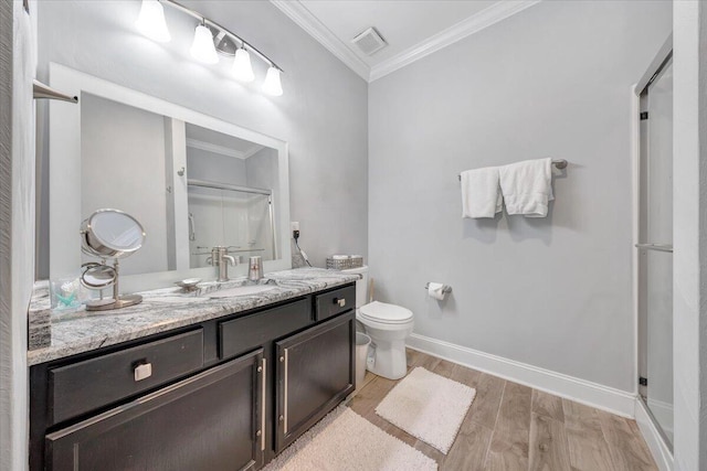 bathroom with ornamental molding, a shower with shower door, hardwood / wood-style floors, vanity, and toilet