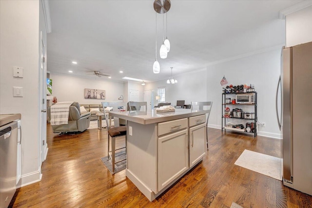 kitchen featuring a center island, appliances with stainless steel finishes, hardwood / wood-style flooring, a breakfast bar area, and decorative light fixtures