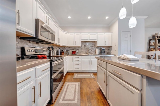 kitchen featuring white cabinetry, ornamental molding, light wood-type flooring, appliances with stainless steel finishes, and tasteful backsplash