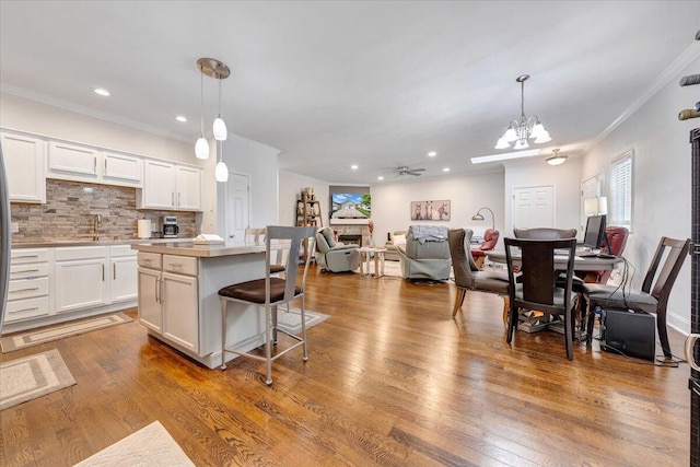 kitchen featuring wood-type flooring, hanging light fixtures, and white cabinetry