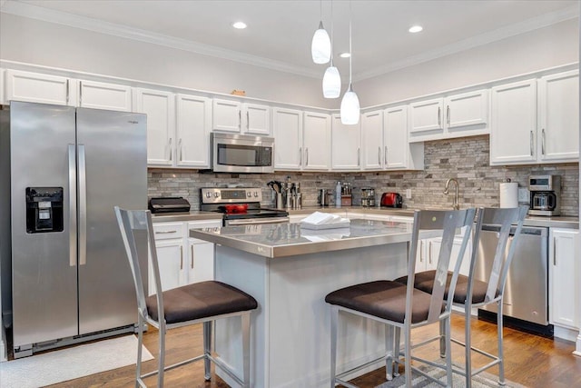 kitchen featuring tasteful backsplash, pendant lighting, dark wood-type flooring, a kitchen island, and appliances with stainless steel finishes